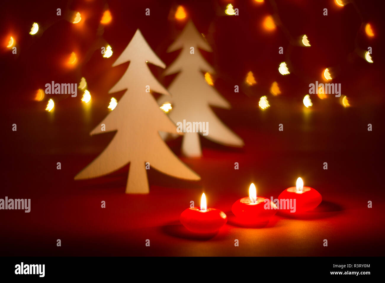 Christmas candles and ornaments over red dark background shaped bokeh with lights Stock Photo