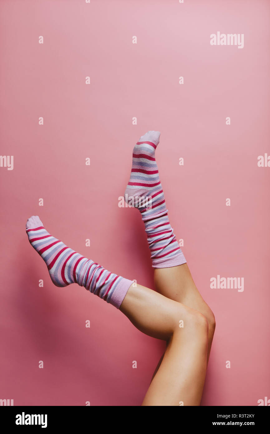 Legs And Feet With Cute Sock. Woman Wearing Pastel Pink And Yellow Socks  Raised Crossed Leg Isolated On Gray Background. Top View. Beauty And  Fashion Concept. Minimalism Fashionable Winter Set. Stock Photo