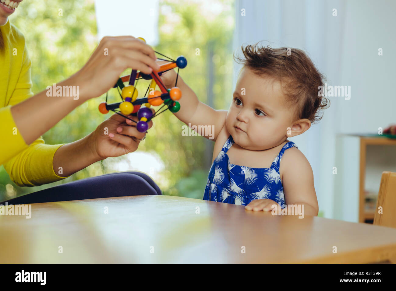 Mother and baby daughter playing at table at home Stock Photo