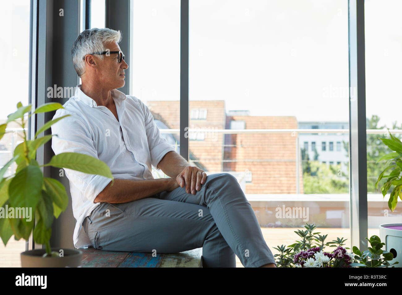 Pensive mature man sitting at the window at home Stock Photo