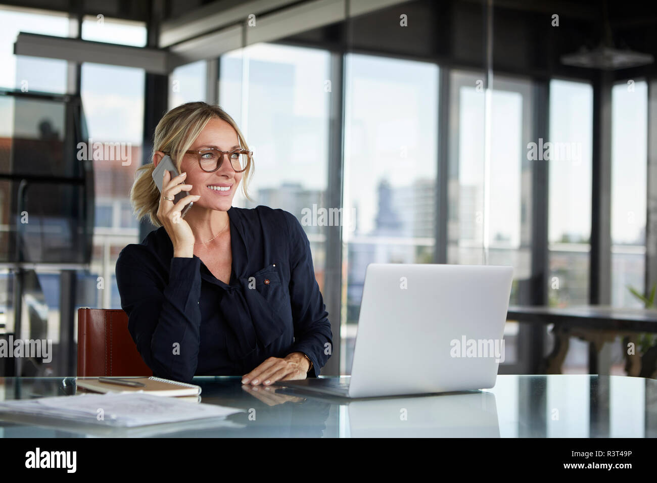 Businesswoman sitting in office, talking on the phone Stock Photo