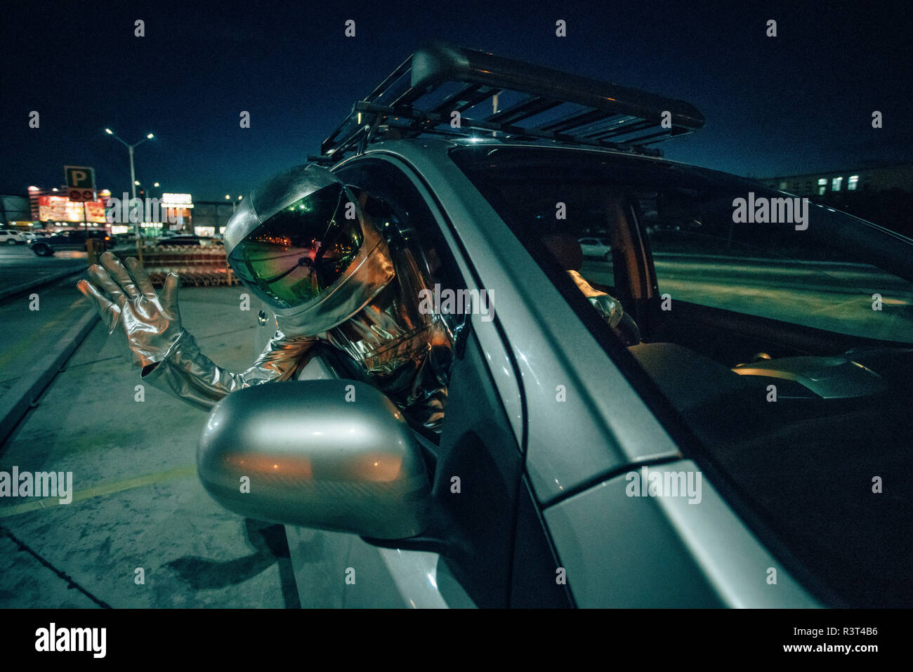 Spaceman waving out of car at night Stock Photo