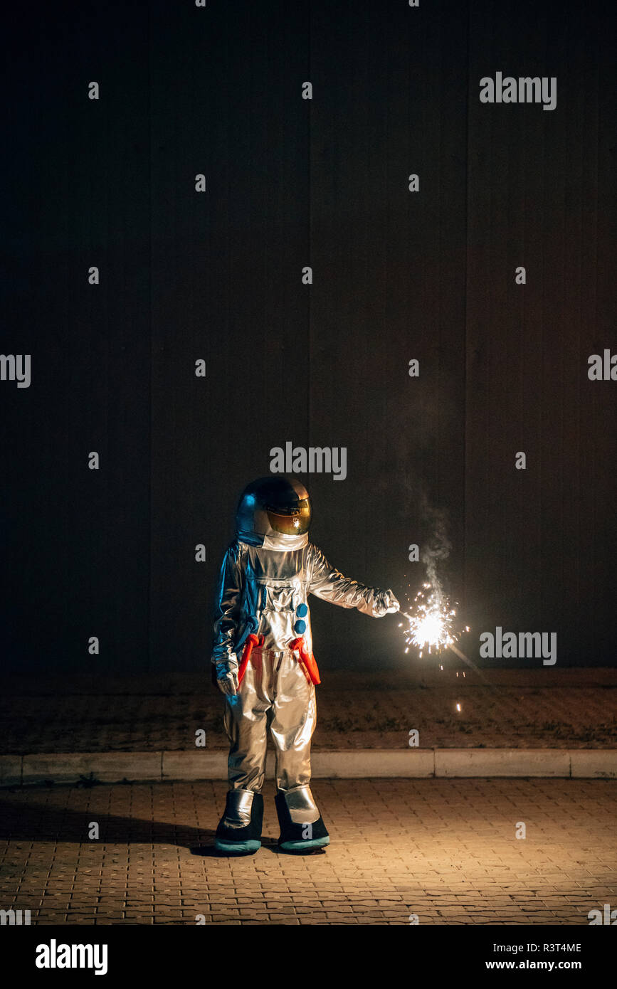 Spaceman standing on a road at night holding sparkler Stock Photo - Alamy