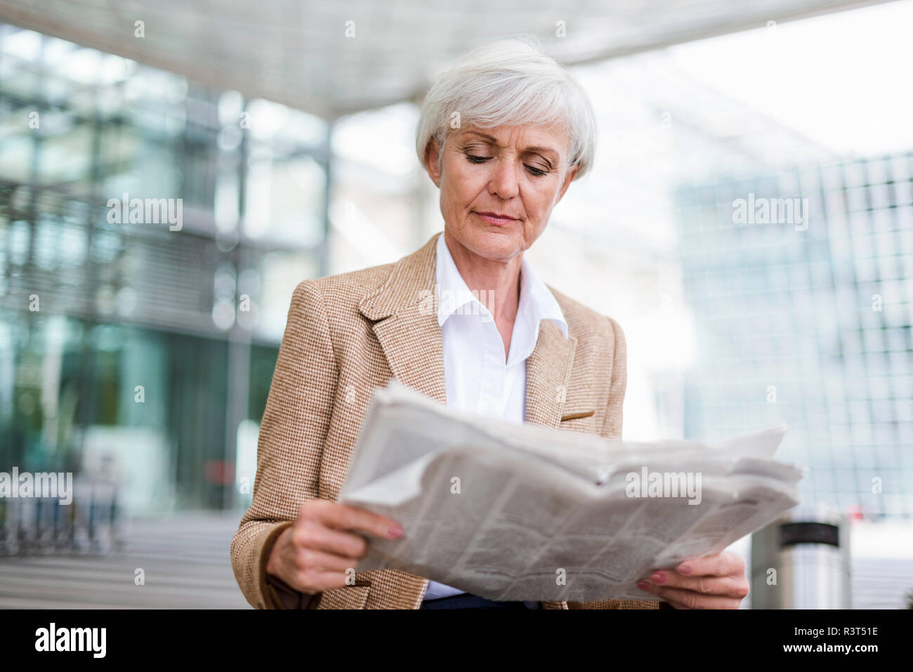 Senior businesswoman in the city reading newspaper Stock Photo