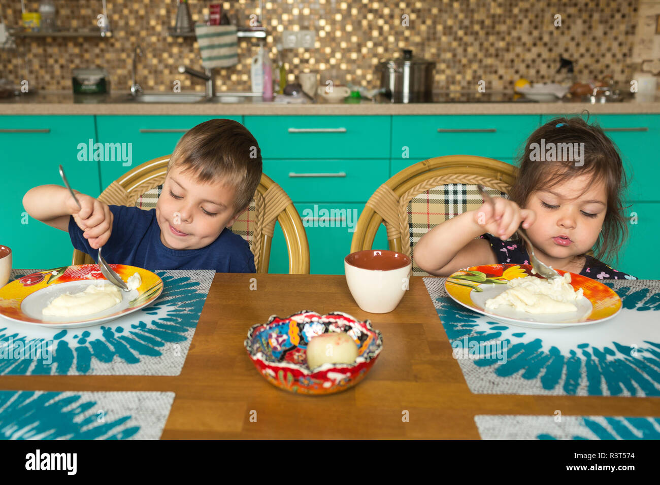 Portrait of boy and his little sister eating breakfast in the kitchen Stock Photo