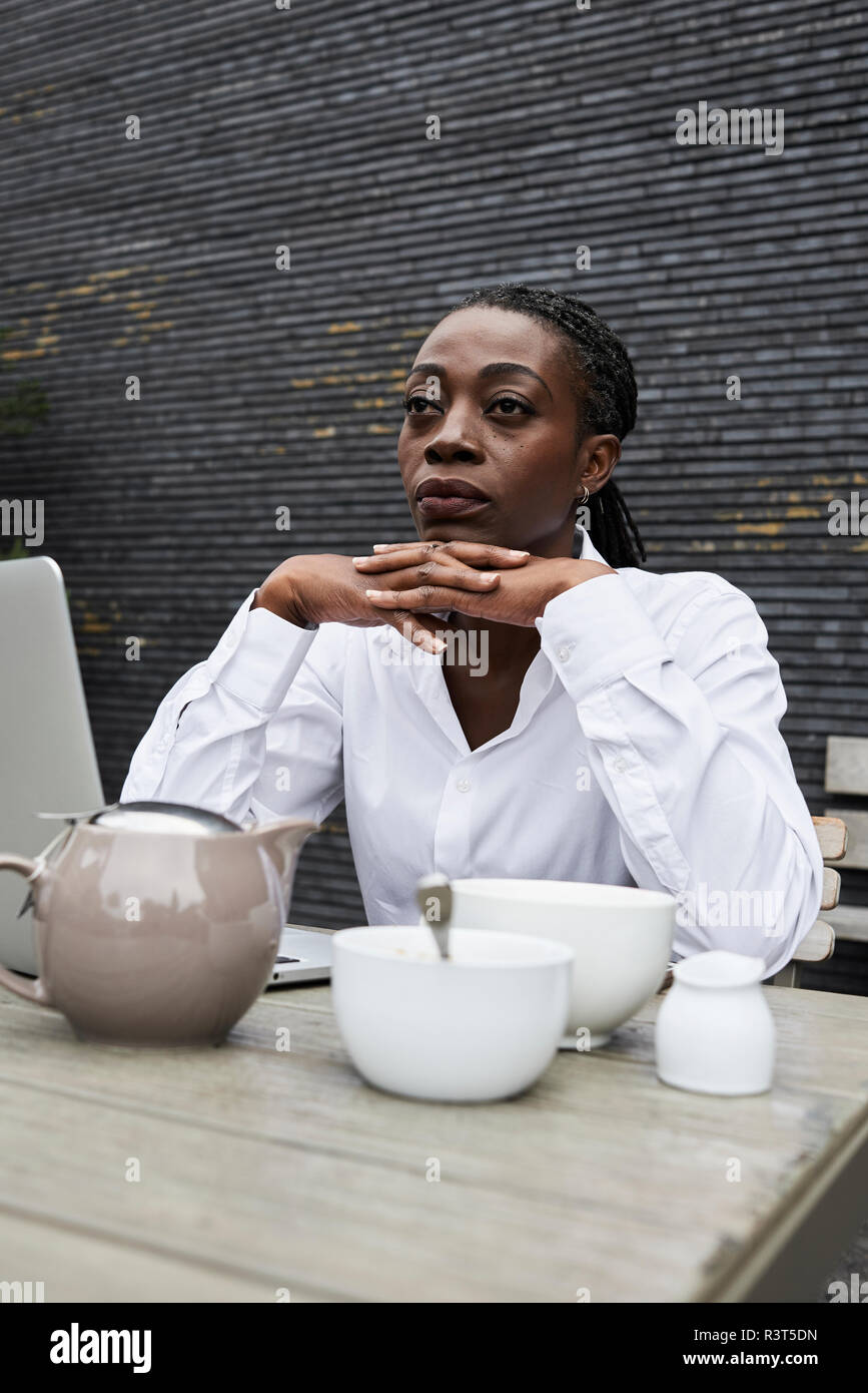 Portrait of pensive businesswoman sitting on terrace of a coffee shop Stock Photo