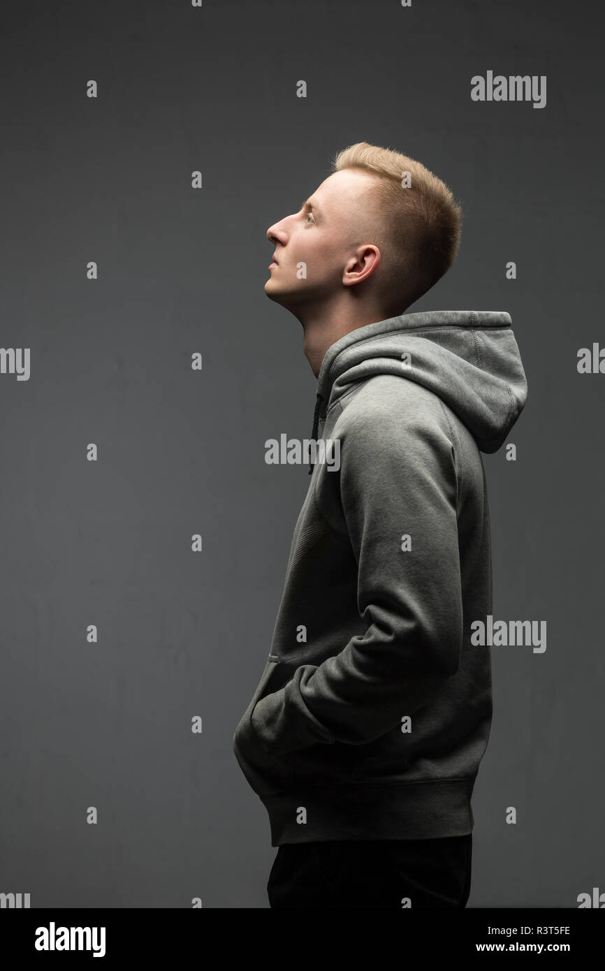 Profile of blond young man wearing grey hooded jacket Stock Photo