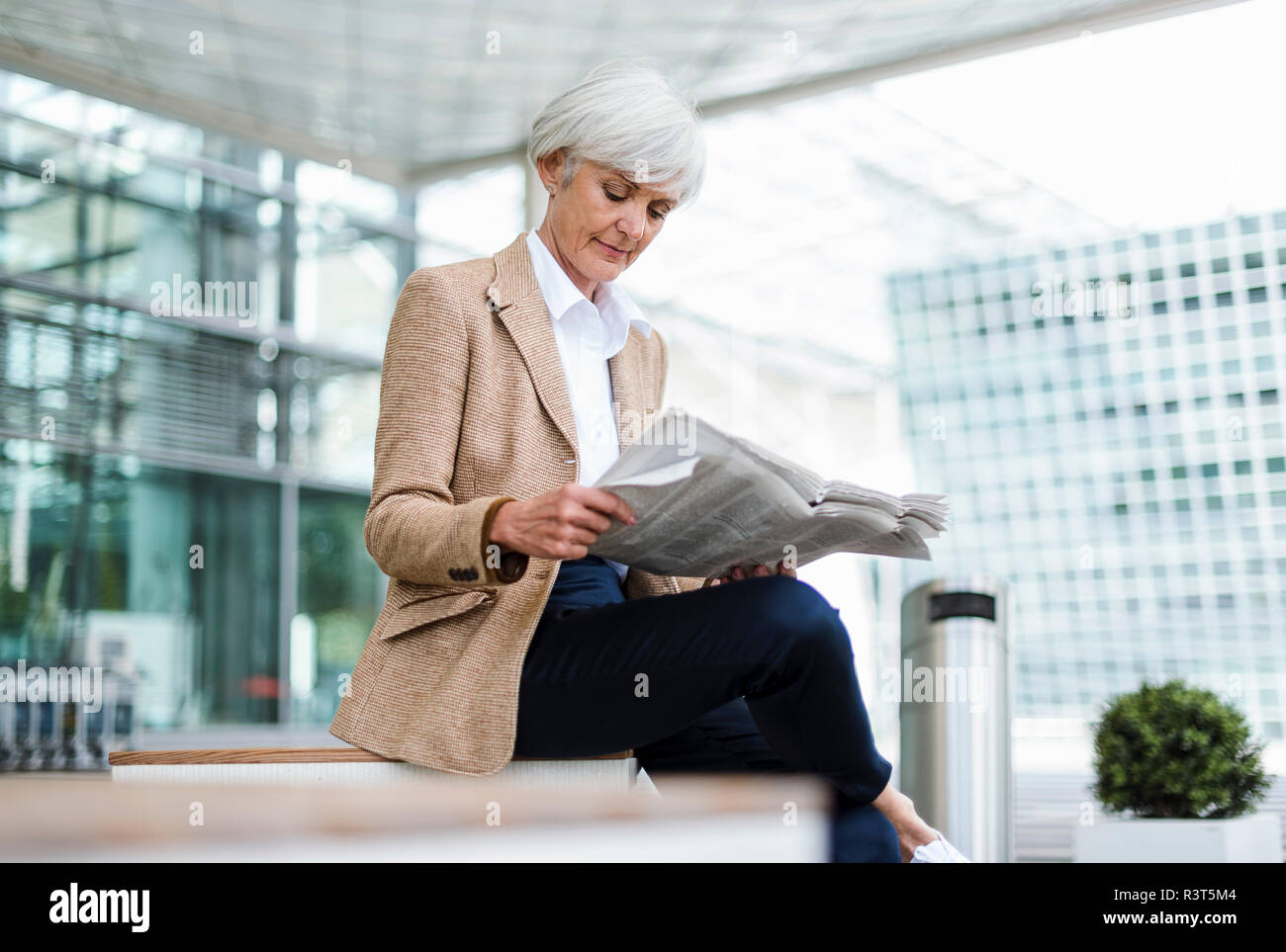 Senior businesswoman sitting in the city reading newspaper Stock Photo