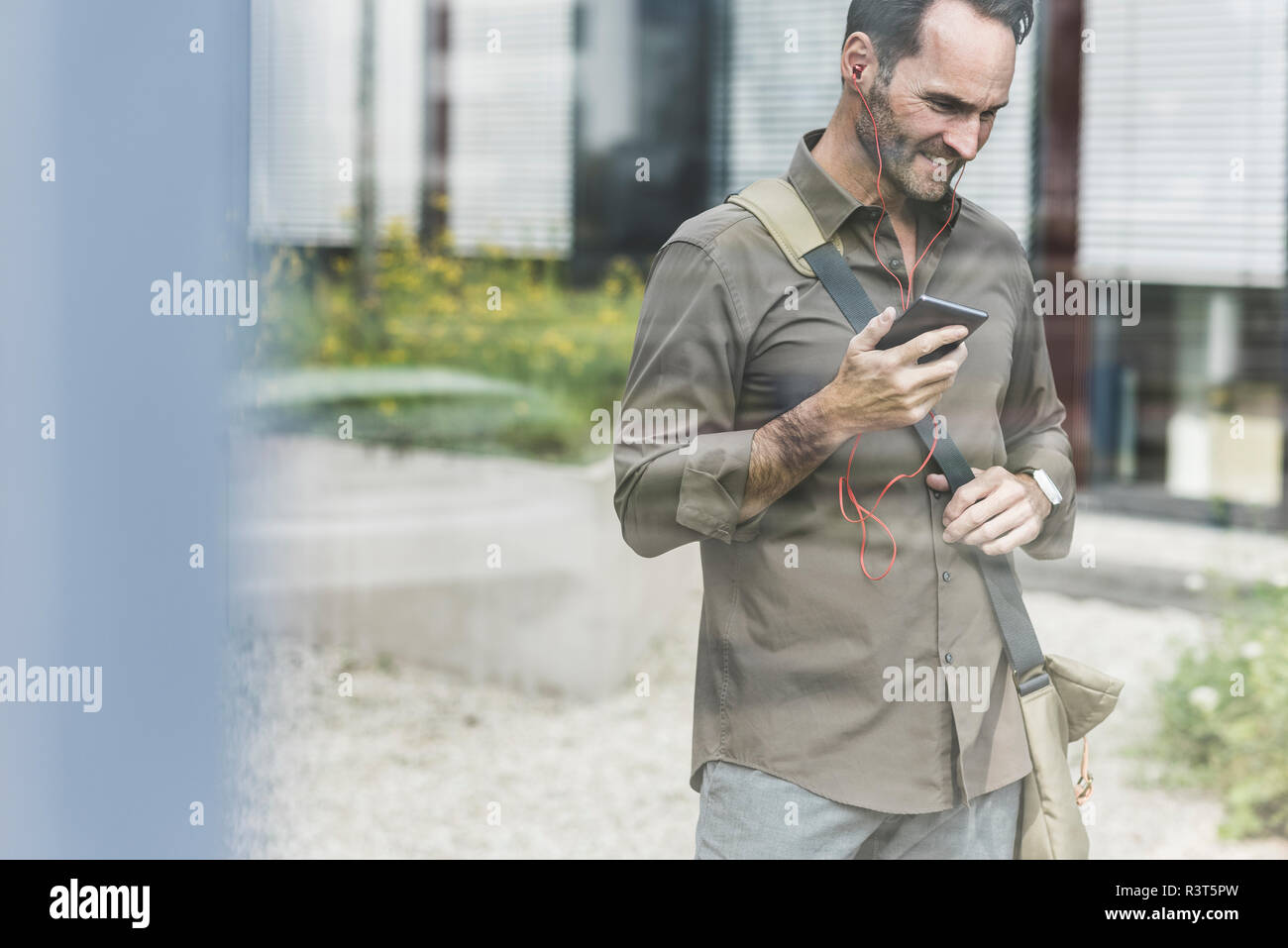Portrait of smiling businessman using smartphone and earphones Stock Photo