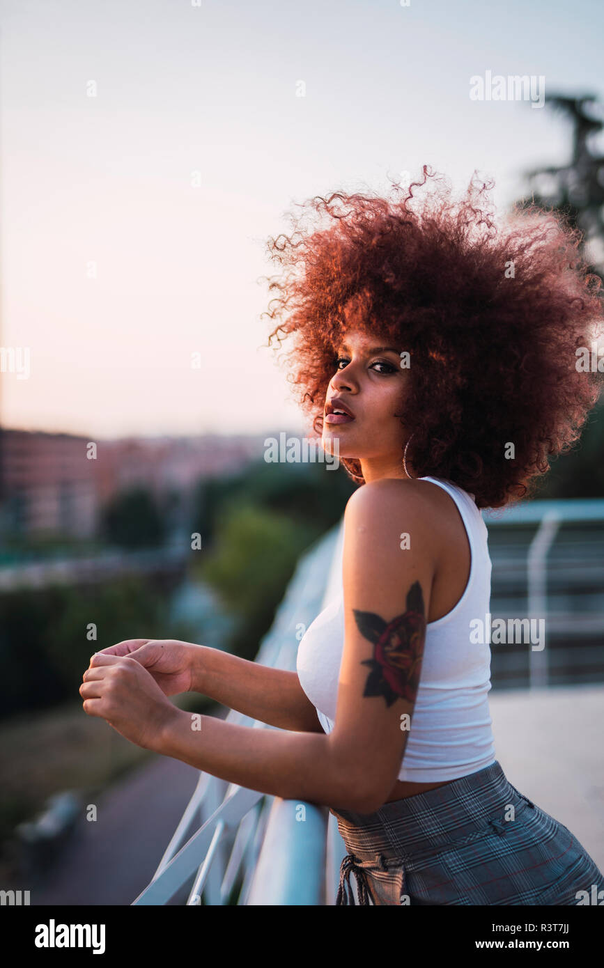 Portrait of young woman standing on terrace at evening twilight Stock Photo