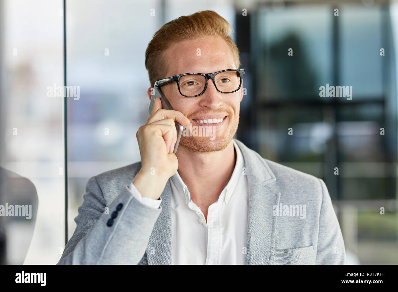 Portrait of smiling redheaded businessman on cell phone Stock Photo