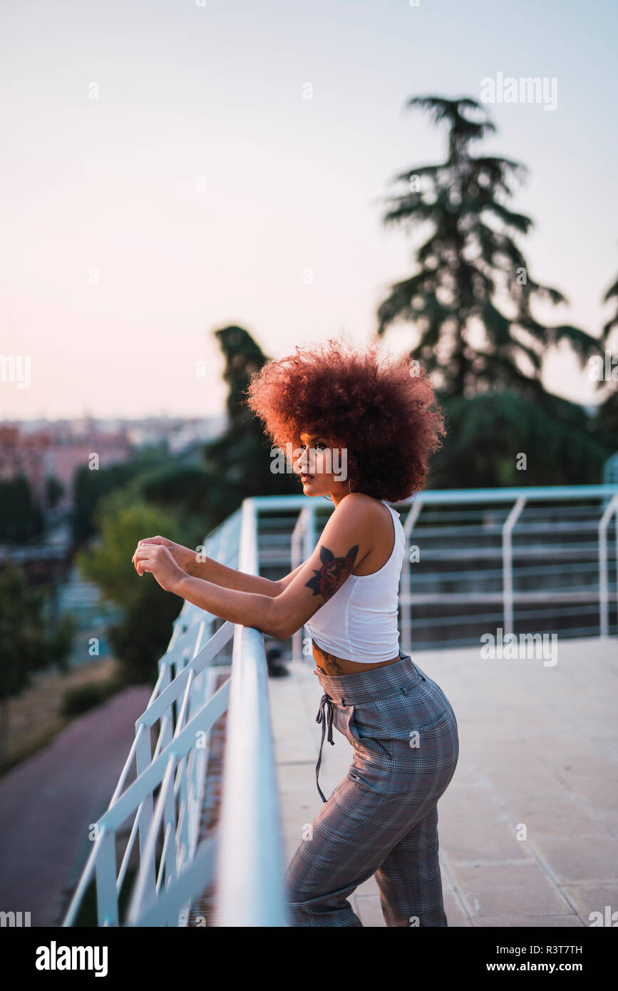 Portrait of pensive young woman on terrace at evening twilight Stock Photo