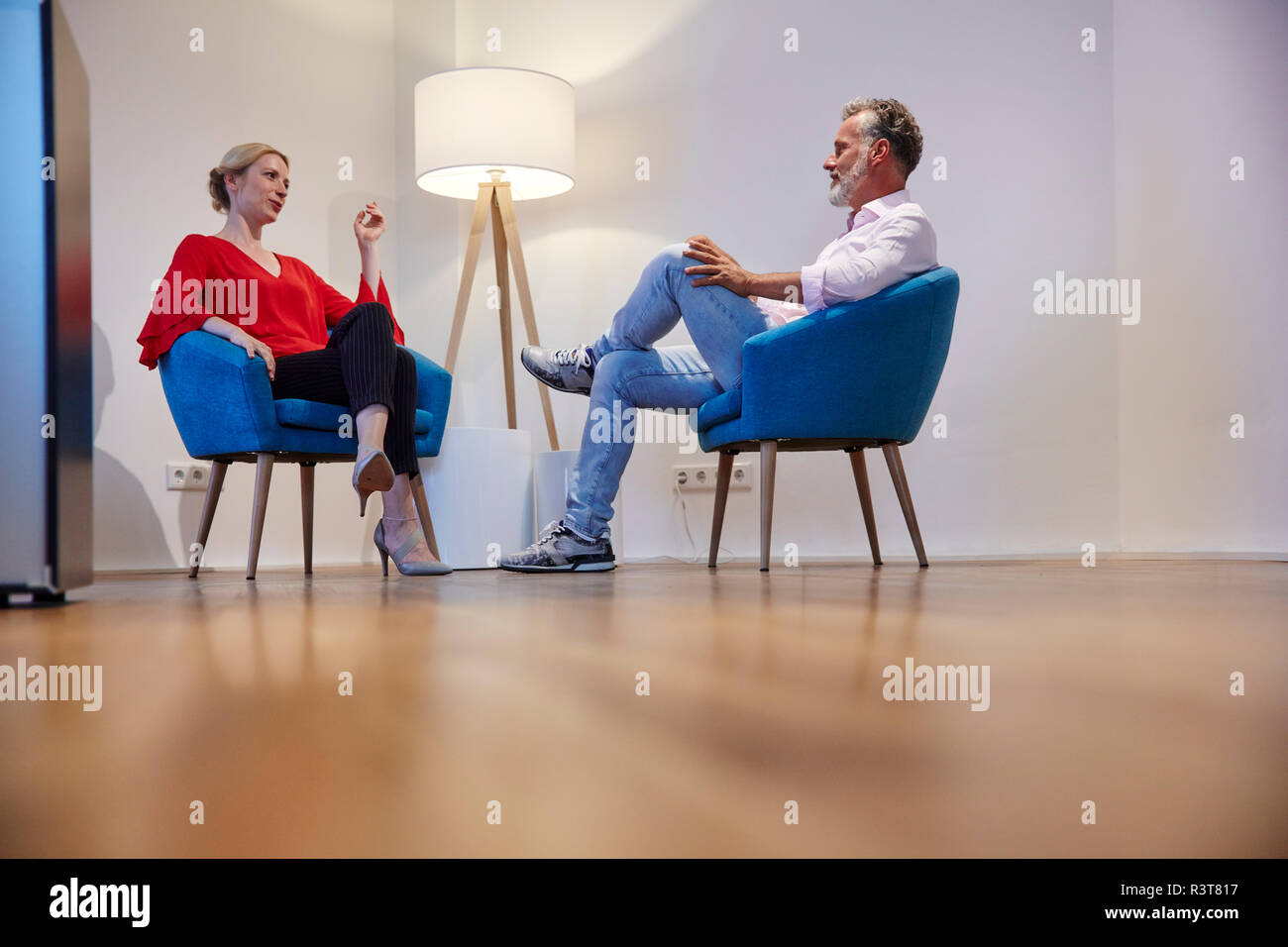 Mature man and young woman sitting in armchairs talking Stock Photo
