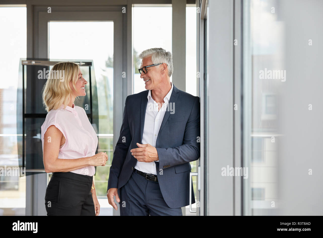 Businessman and woman standing in office, discussing project Stock Photo