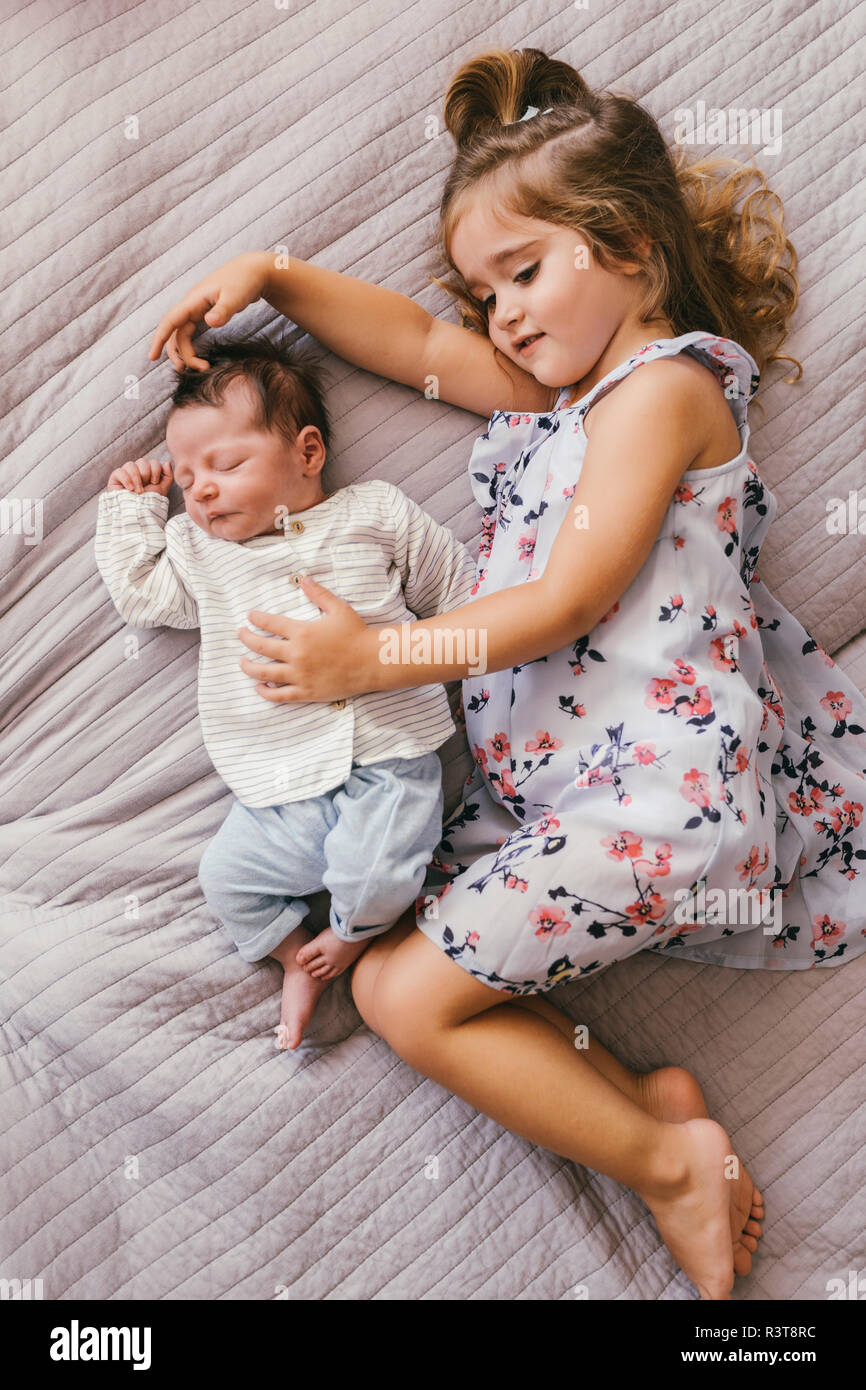 Girl lying on blanket cuddling with her baby brother Stock Photo