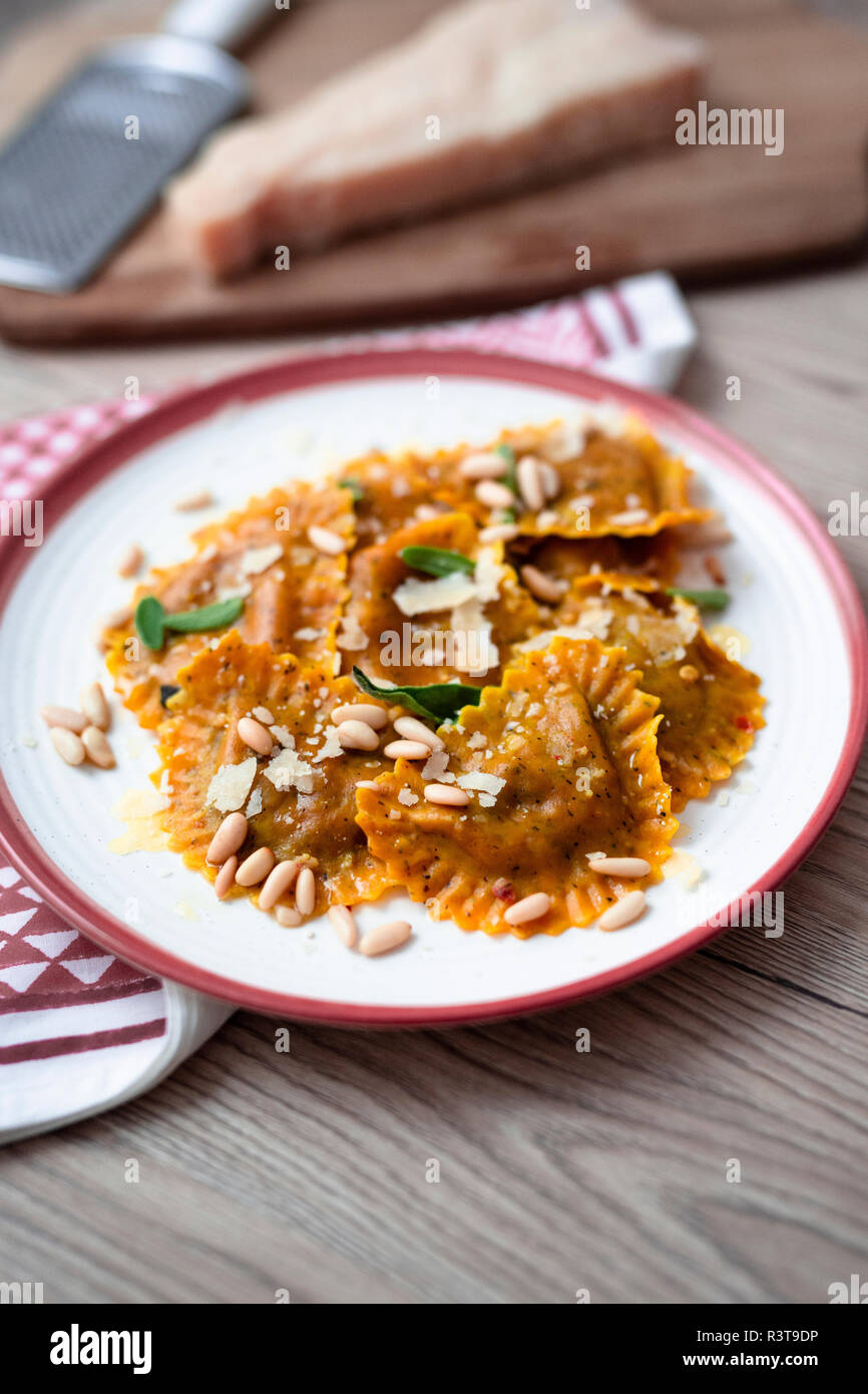 Plate of pumpkin ravioli with sage leaves, parmesan and pine nuts Stock Photo
