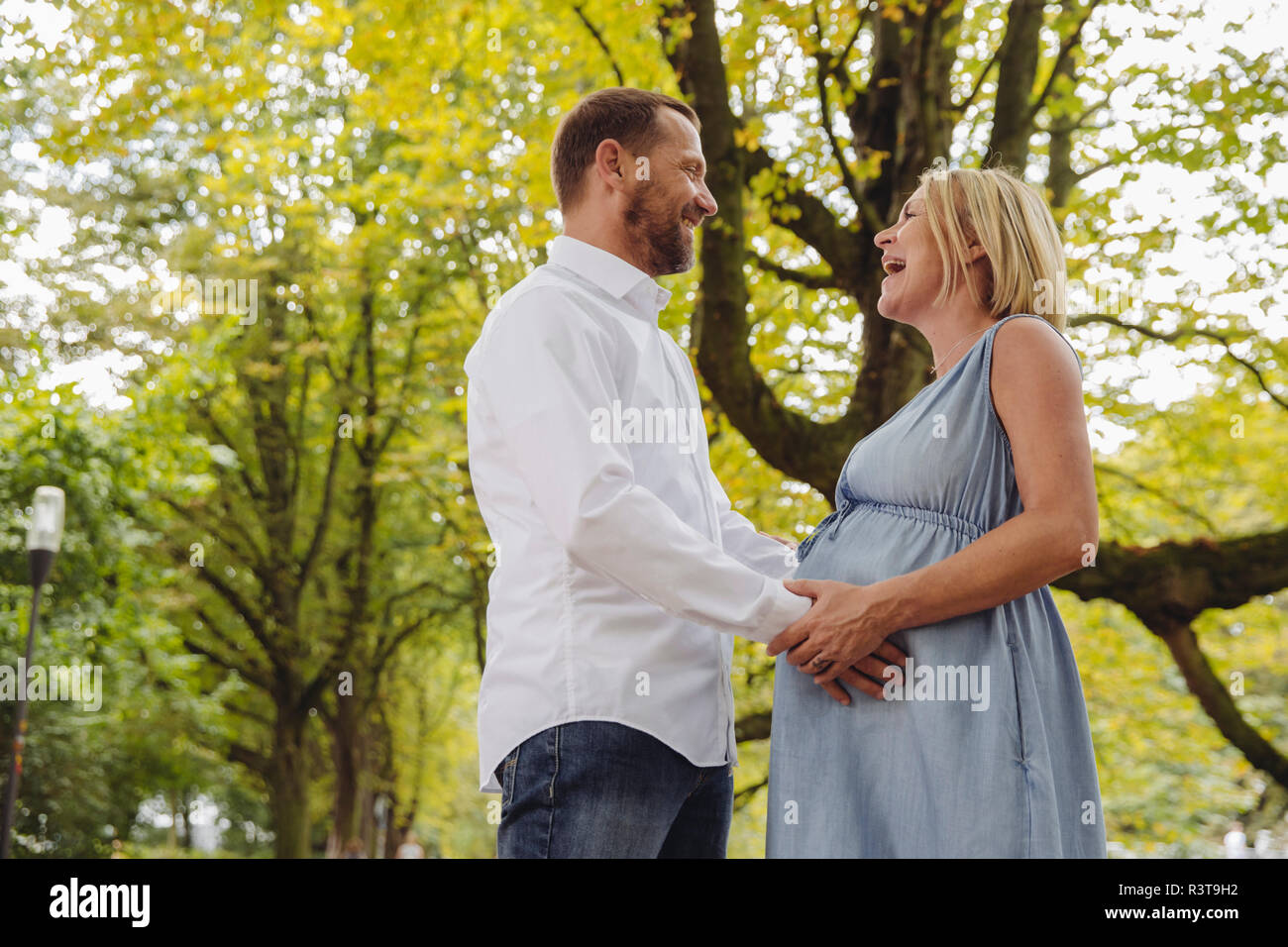 Happy mature pregnant couple talking in park Stock Photo