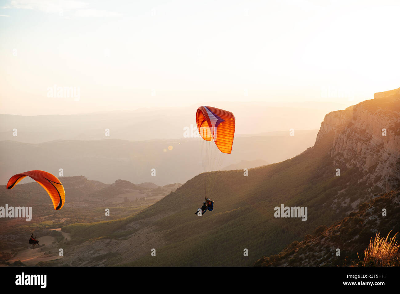 Spain, Silhouette of paraglider soaring high above the mountains at sunset Stock Photo