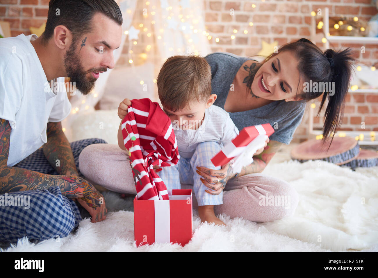 Boy opening Christmas present with his parents in bed Stock Photo