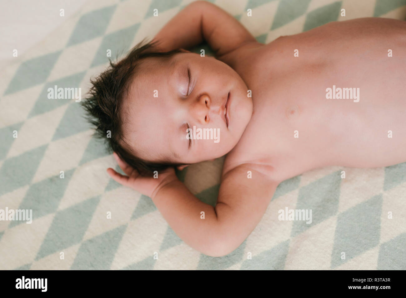 Portrait of a newborn baby boy lying on a blanket with closed eyes Stock Photo