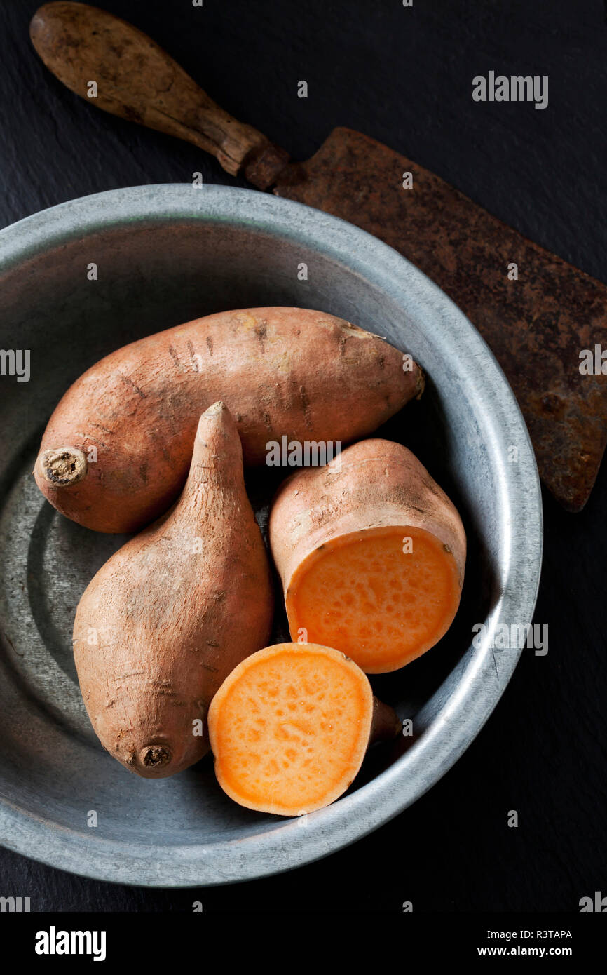 Sliced and whole sweet potato in metal bowl Stock Photo