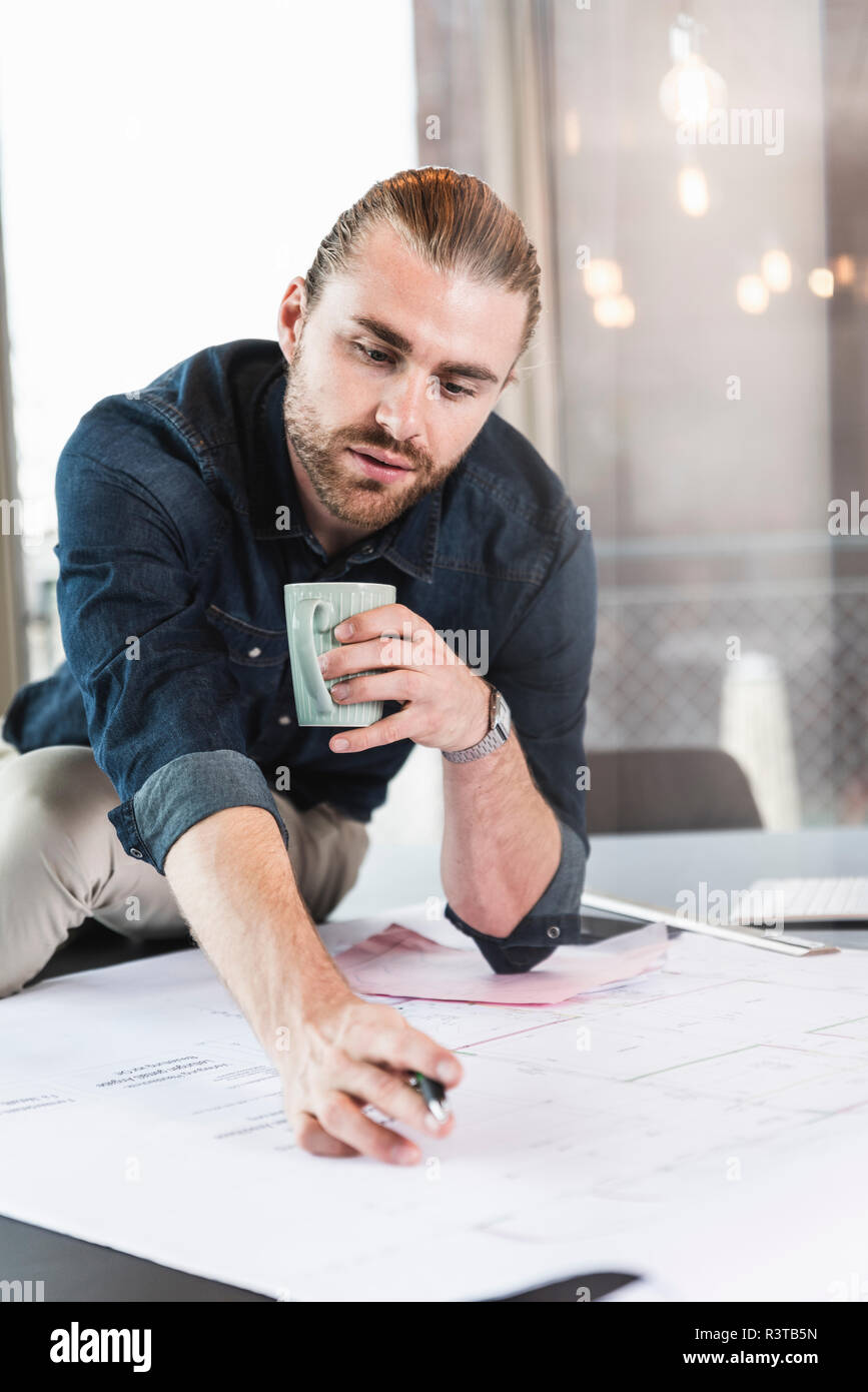 Young businessman working on plan at desk in office Stock Photo