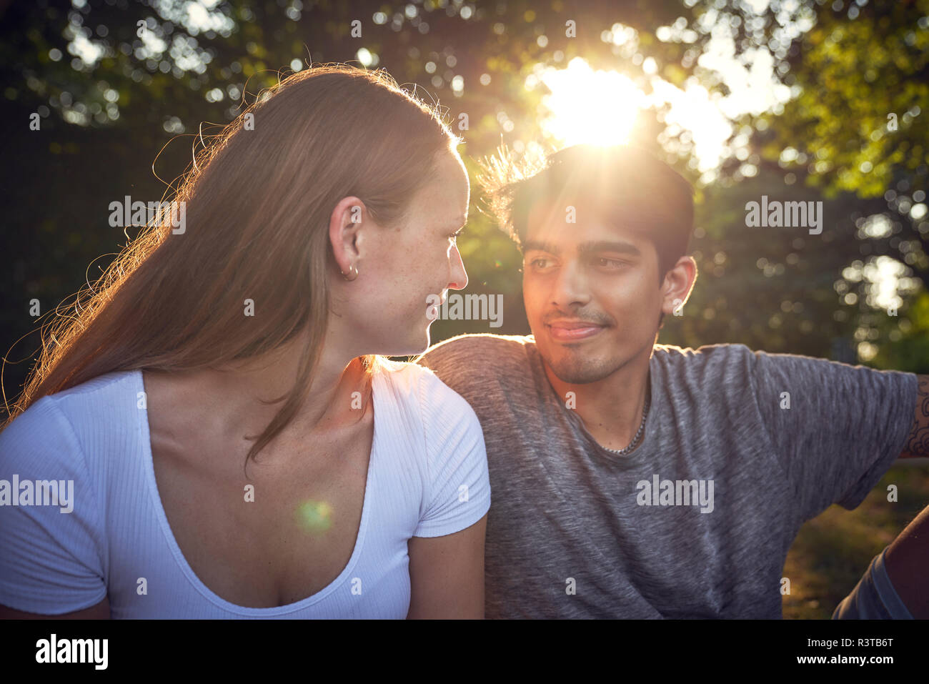 Romantic young couple sitting in park, enjoying sunset Stock Photo - Alamy