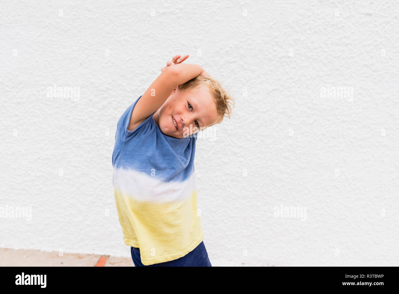 Blond boy making funny faces on white background. Stock Photo