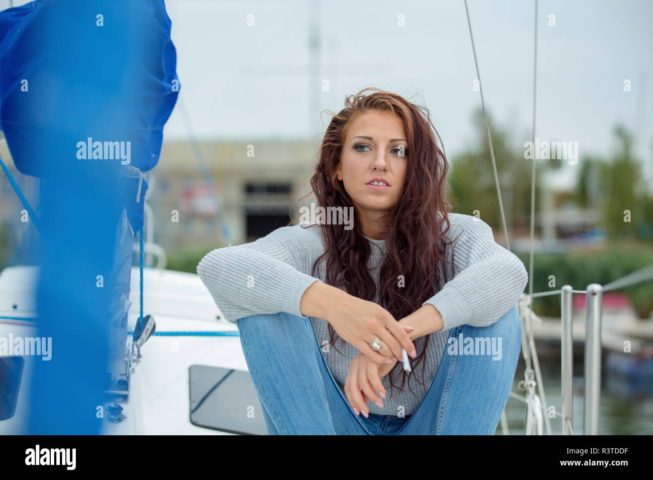 Woman sitting on sailing boat, waiting, smoking cigarette Stock Photo