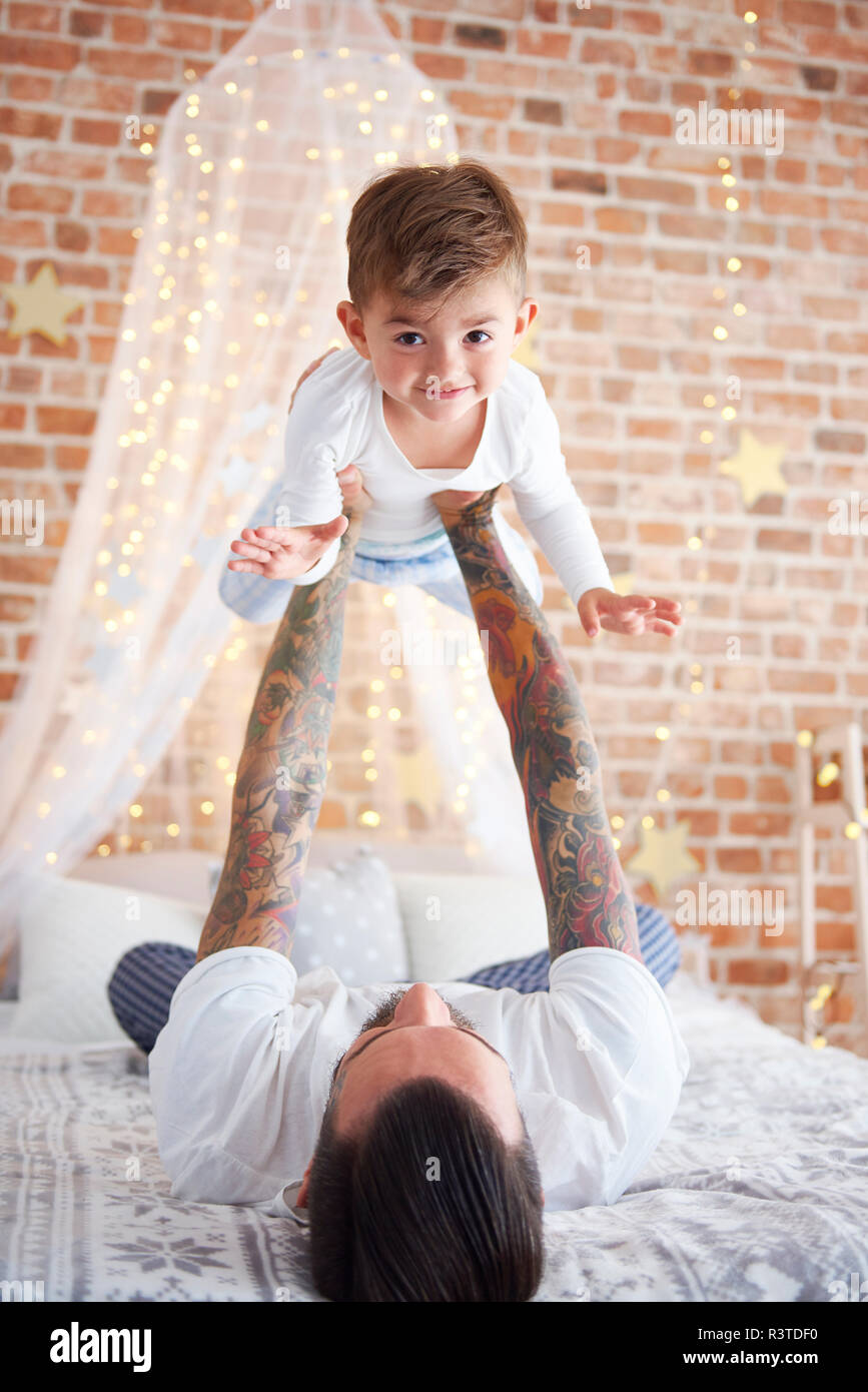 Father lifting up son at Christmas time in bed Stock Photo