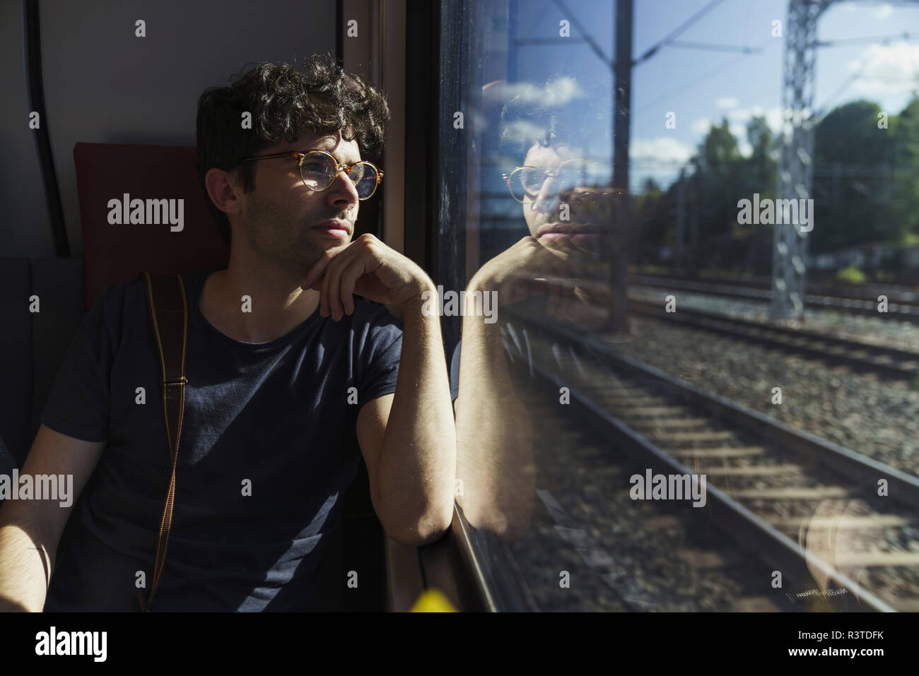 Man traveling by train looking out of window Stock Photo