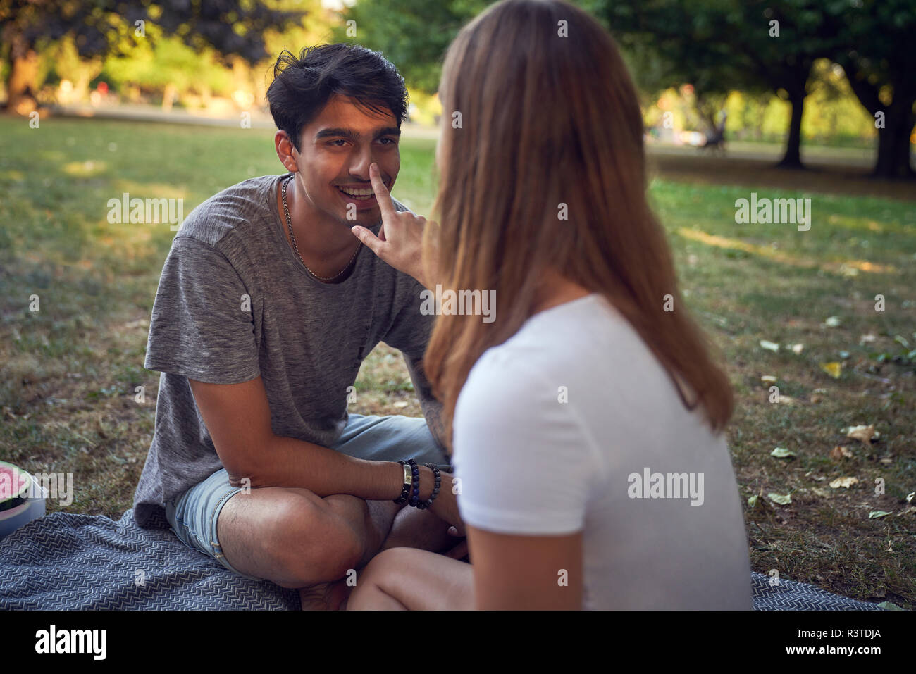 Young couple sitting in park, having fun Stock Photo