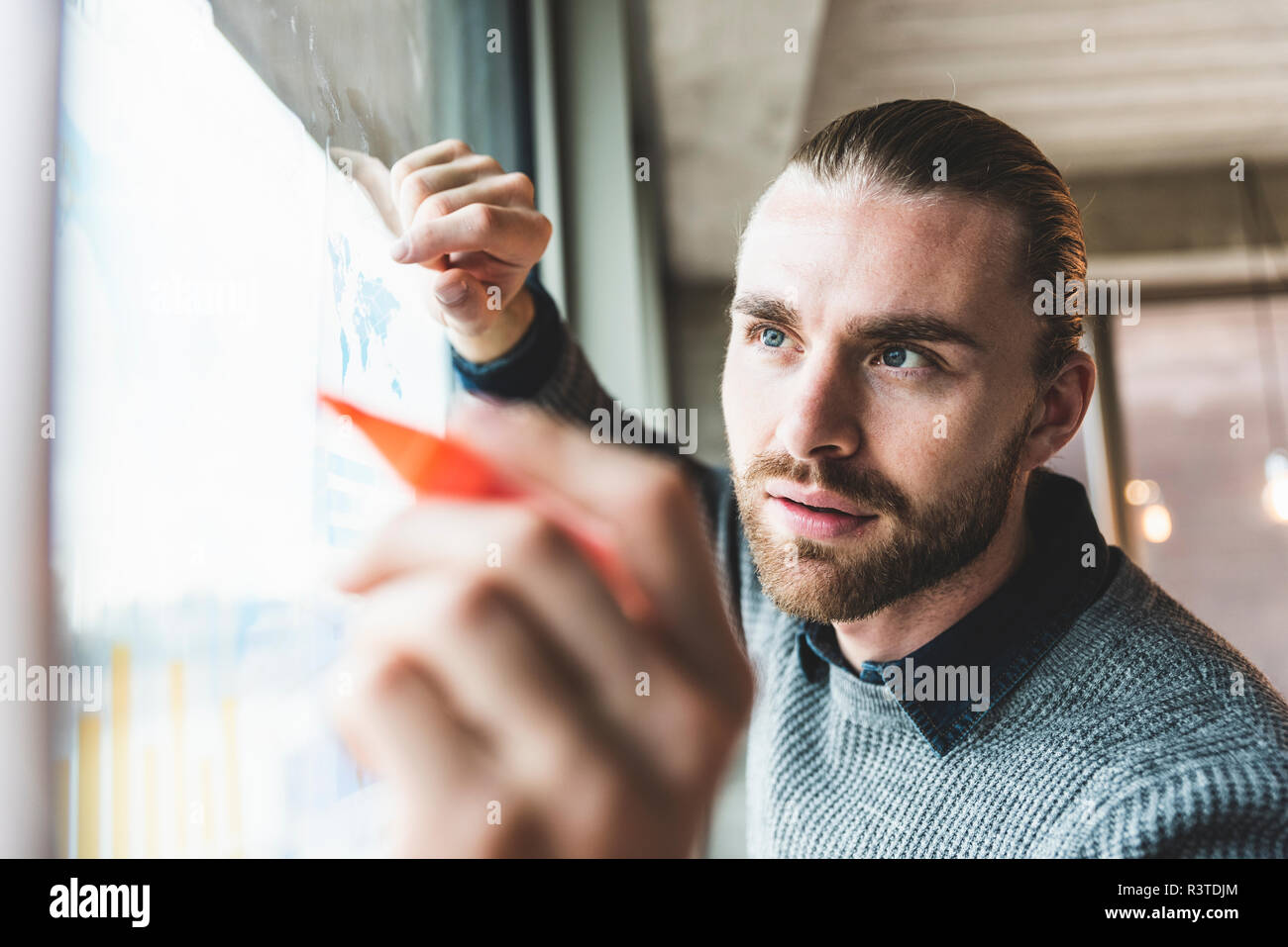 Young businessman working on data at windowpane Stock Photo
