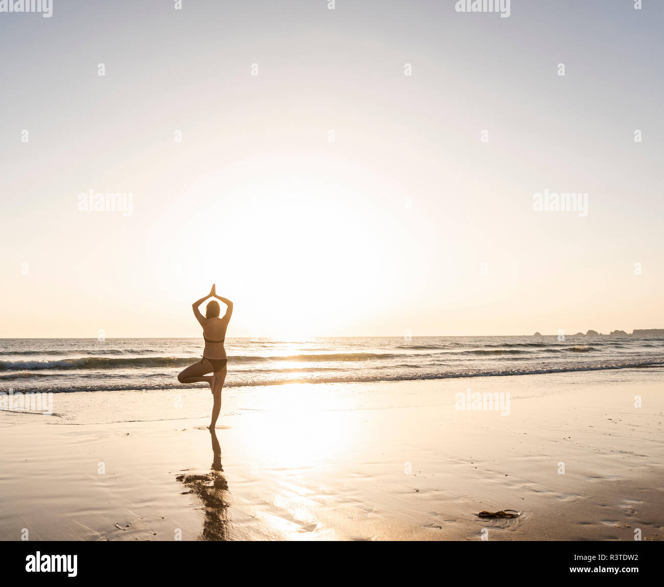 Young woman practicing yoga on the beach Stock Photo