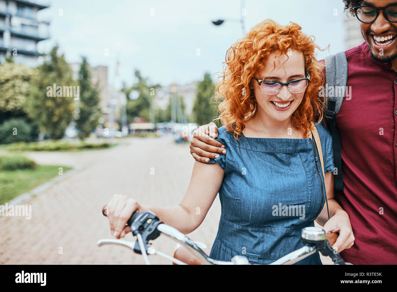 Friends walking in park, talking, woman pushing bicycle Stock Photo