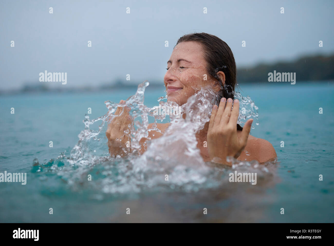 Young woman bathing in lake splashing with water Stock Photo