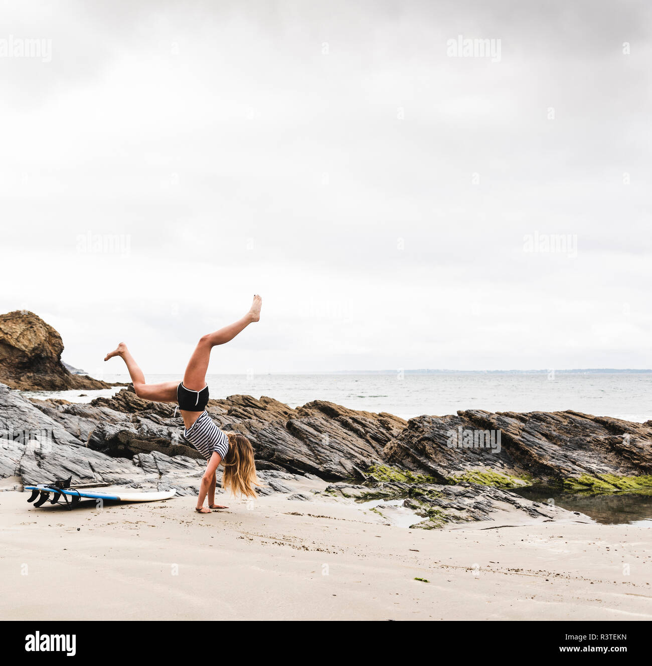 Young woman with surfboard doing handstand on the beach Stock Photo Alamy