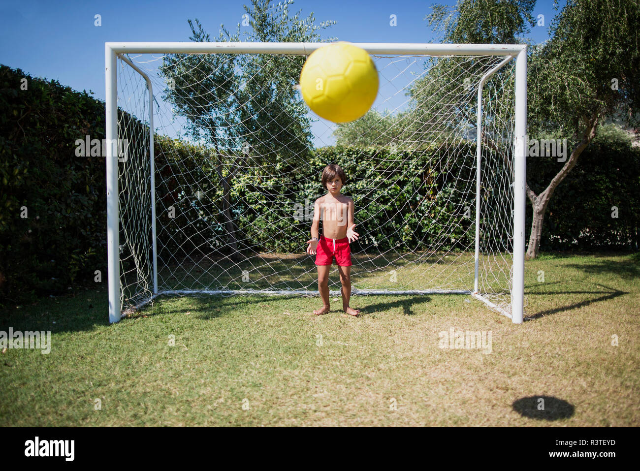 Little boy standing in front of soccer goal watching football Stock Photo