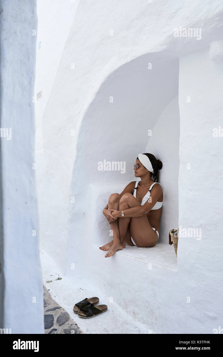 Young woman wearing white bikini  sitting in a wall niche Stock Photo