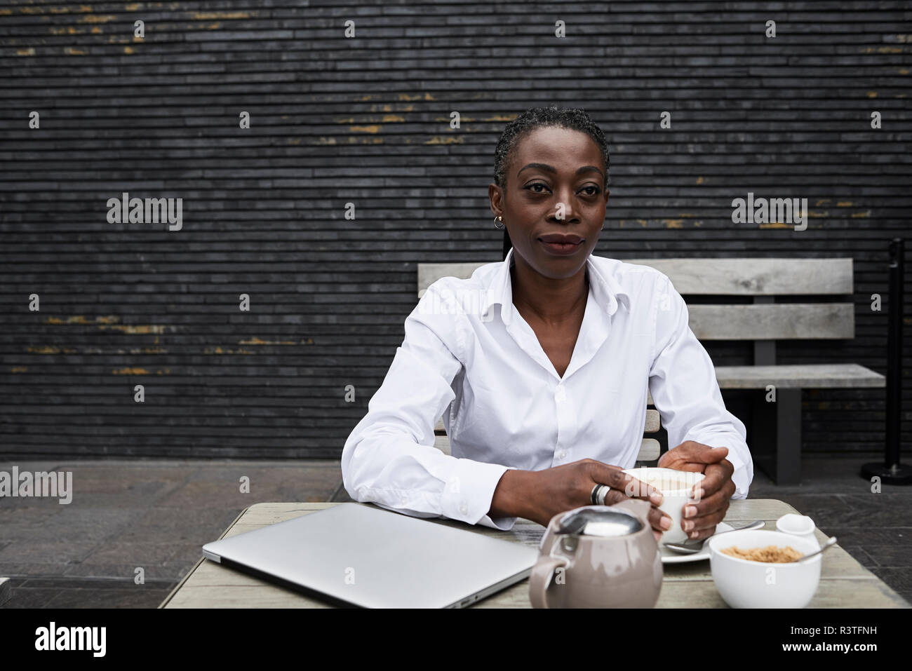 Portrait of businesswoman sitting on  terrace of a coffee shop drinking tea Stock Photo