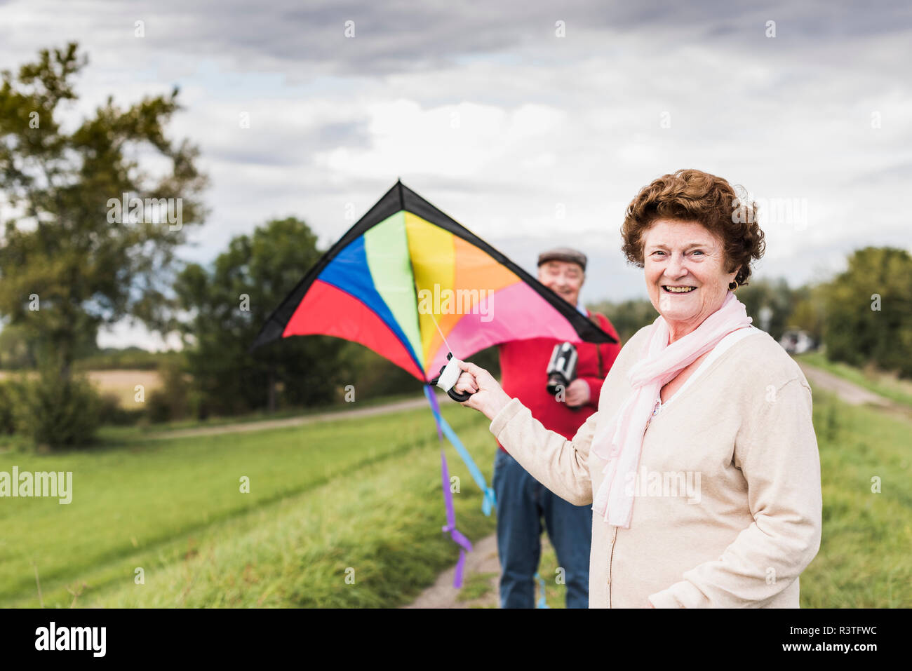 Portrait of smiling senior couple with kite in rural landscape Stock Photo