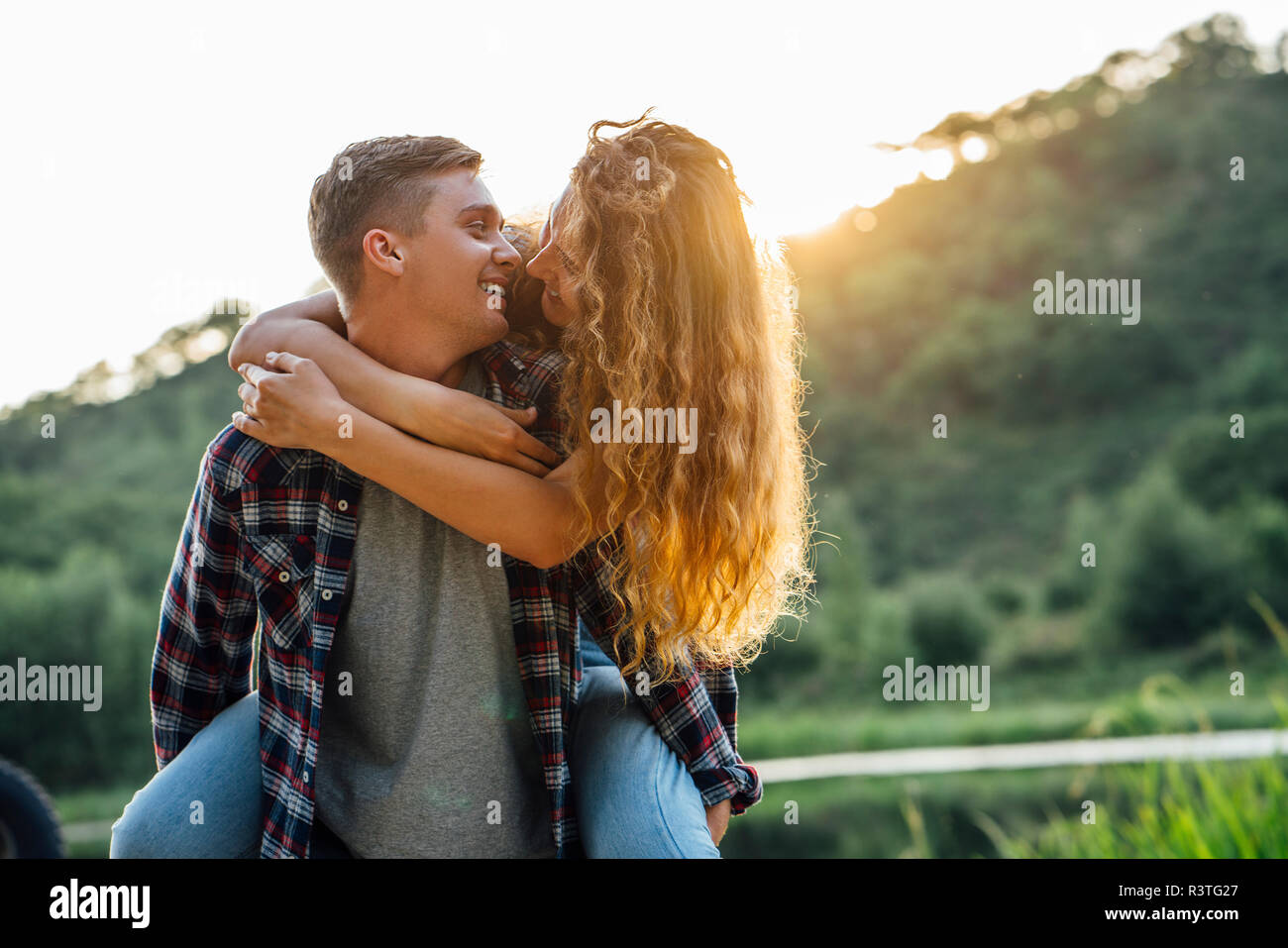 Romantic couple spending time in nature, kissing at sunset Stock Photo