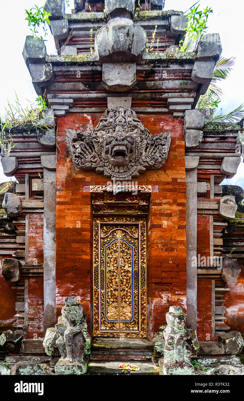 Gold door in Ubud Indonesia with red brick and stone statues. Stock Photo