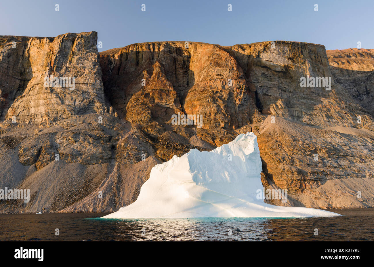 Landscape with steep yellow cliffs and icebergs in the Uummannaq fjord ...