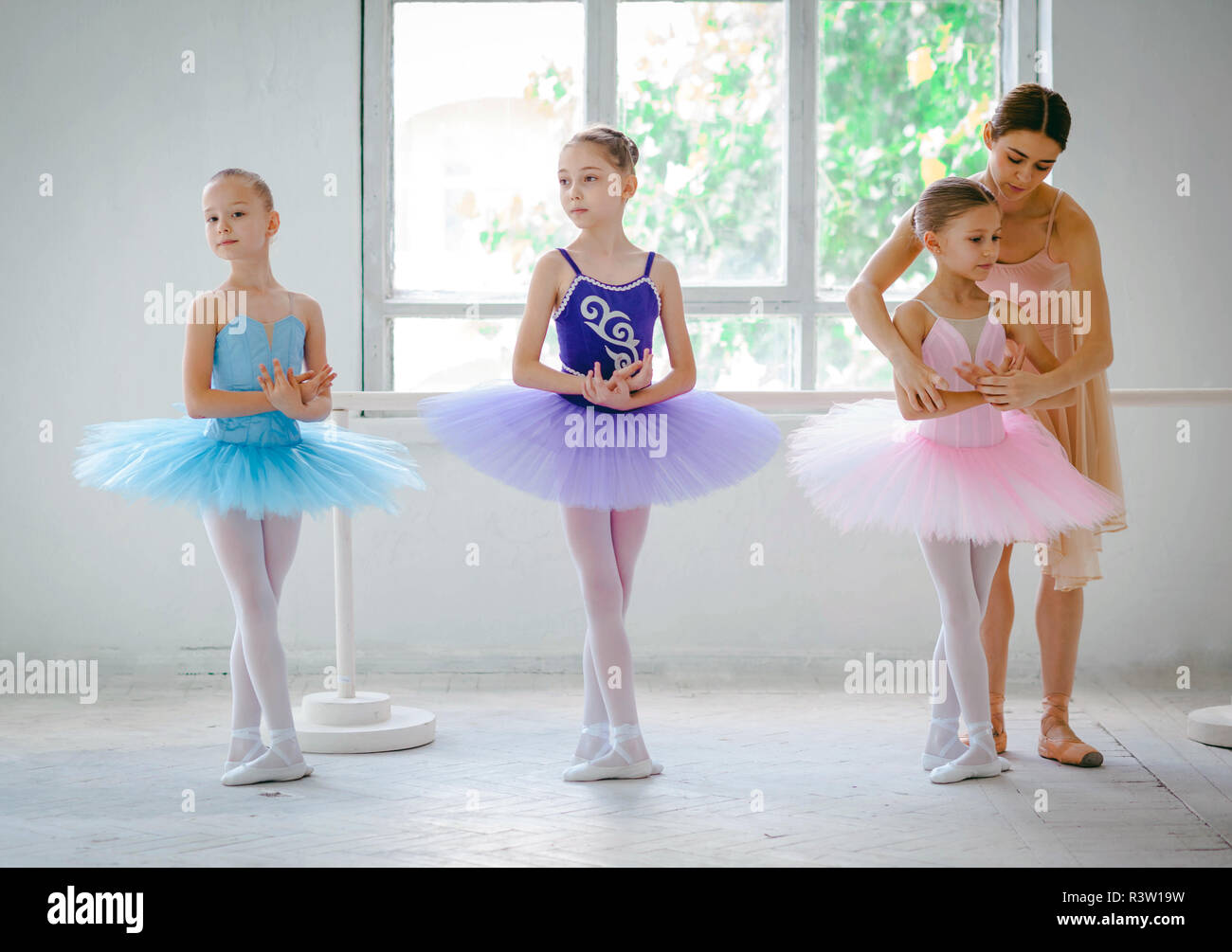 Three little ballerinas with personal ballet teacher in dance studio Stock Photo