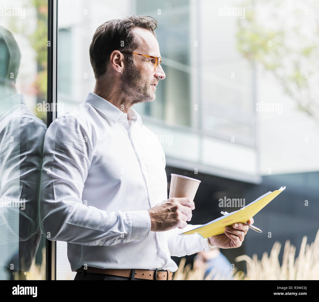 Businessman with papers and coffee to go looking at distance Stock Photo