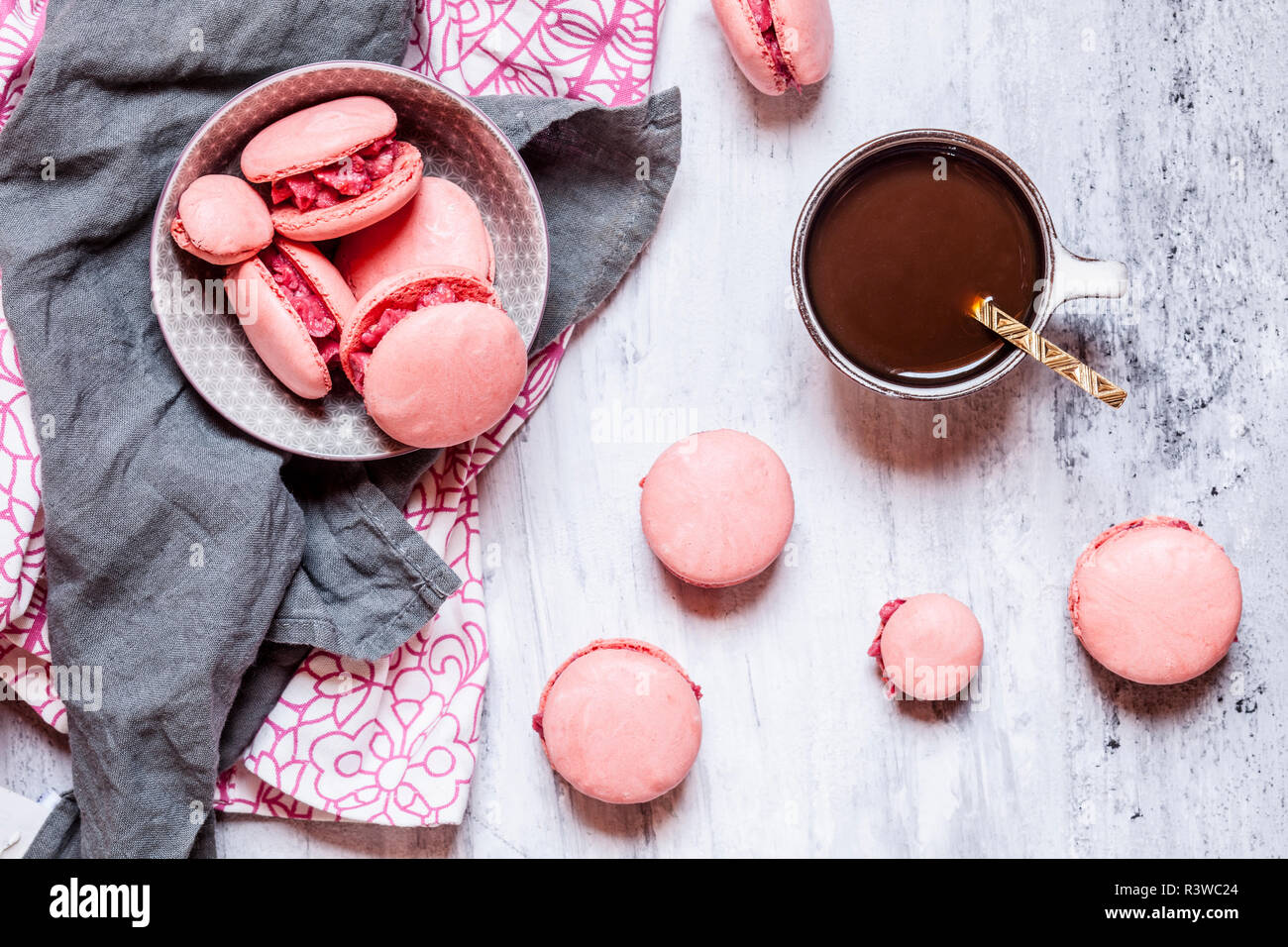 Pink macarons filled with raspberry buttercream and a cup of coffee