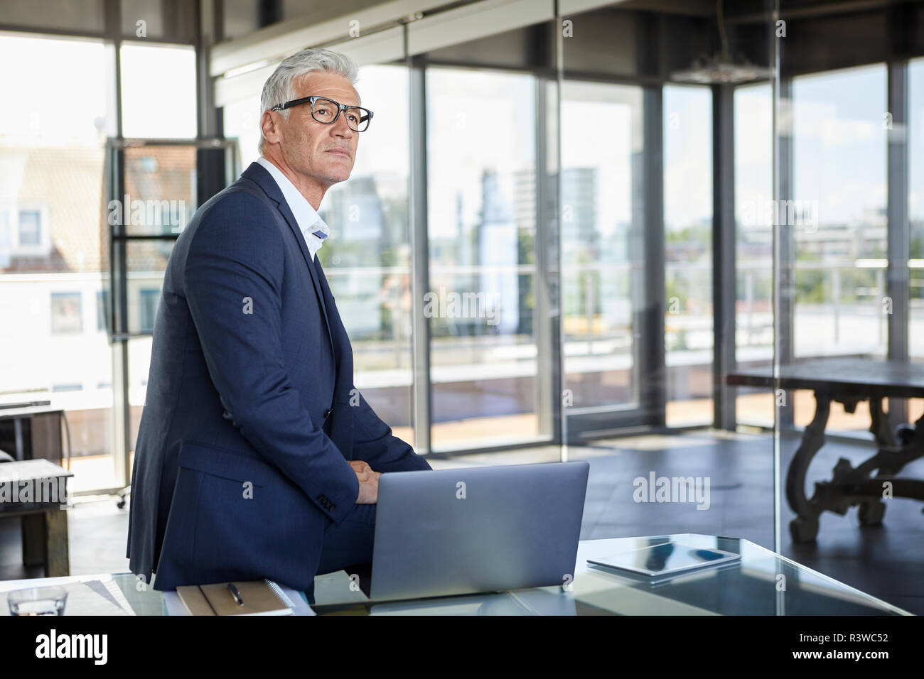 Successful manager sitting on desk, thinking Stock Photo