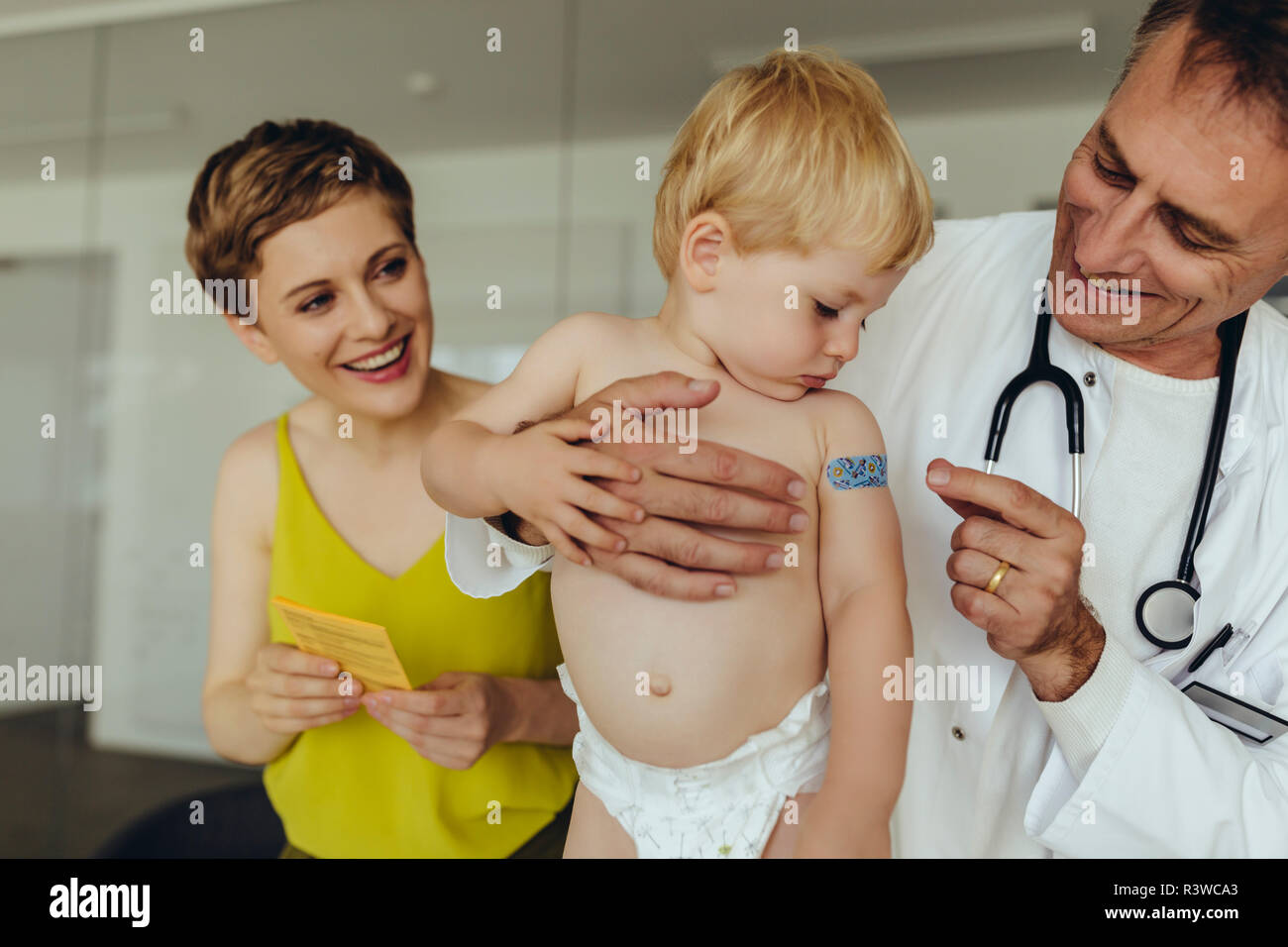 Doctor putting band aid on toddler's arm after vaccination Stock Photo