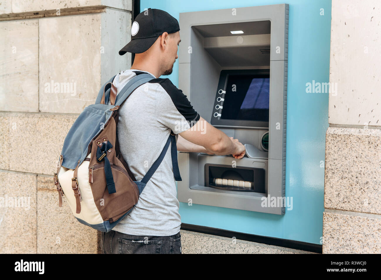 The tourist withdraws money from the ATM for further travel. Finance, credit card, withdrawal of money. Life style. Journey. Vacation. Grabs a card from the ATM. Stock Photo